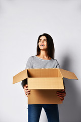 beautiful brunette woman standing on a light background with a moving cardboard box