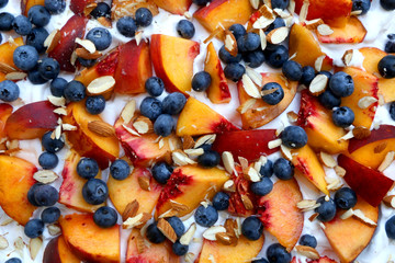 Chocolate Pavlova cake with whipped cream, peaches, blueberries and almonds. Top view.