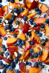 Chocolate Pavlova cake with whipped cream, peaches, blueberries and almonds. Top view.