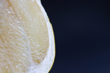 slice of ripe fresh Pamela fruit with juice shot close-up on a black background.