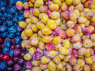 Plums and peaches on the market. The concept of autumn harvest, natural products, fruits. An abundance of fruit.