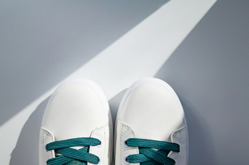 New white sneakers with green laces on a white background. The concept of comfortable comfortable stylish shoes. Place for text, flat lay, minimalism.