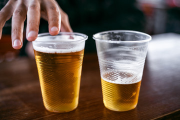 Two plastic glasses with beer stand side by side
