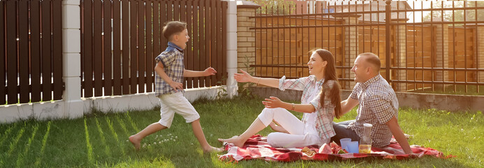 pretty young woman handsome man sit on green yard lawn and happy little son jumps in mother arms...