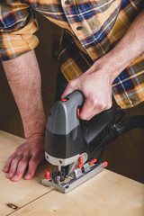 Man with electric jig saw cutting wood