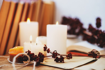  homeliness, hygge, candles, old books, diary and dried flowers on a wooden background, vintage
