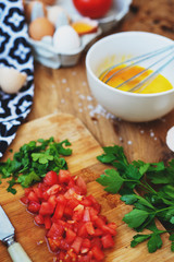 cooking process, ingredients, hearty and healthy breakfast, scramble eggs with tomatoes and herbs on toast with black tea on a wooden background