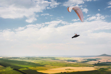 A paraglider flies in the sky in a cocoon suit on a paraglider over the Caucasian countryside with...
