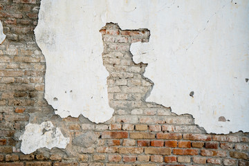 Damaged white plaster on old brick wall