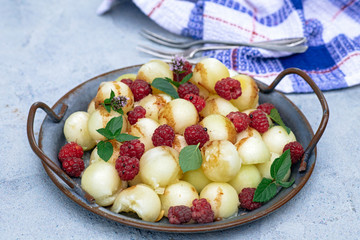 Melon balls and raspberries fruit salad in tray, outdoor shot