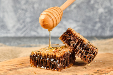 honeycomb with honey on a wooden Board, with a spoon for honey pours slowly honey selective focus