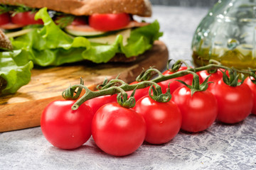 Sandwich with cheese, cucumber and Cherry Tomato on a wooden board. The sandwich is decorated with a lettuce leaf and cherry tomatoes.