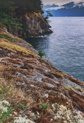 Sunset colours and rocky beaches with bluffs and cliffs in Apodaca Provincial Park on Bowen Island....