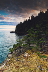 Sunset colours and rocky beaches with bluffs and cliffs in Apodaca Provincial Park on Bowen Island....