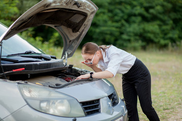 Obraz na płótnie Canvas Young woman by the roadside after her car has broken down She opened the hood to see the damage