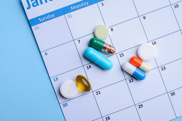 Different medical pills lay on calendar. Concept of taking pills on time, regularly, impossible to live without medicine