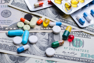 Different colorful pills capsules on money bills. Concept of expensive treatment, medicine, medical...