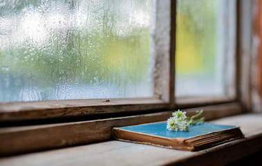 old books on the background of the village wooden wet window, copy space.