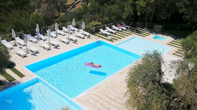 Young woman in bikini air mattress in the big swimming pool