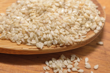 Organic natural sesame seeds on wooden spoon, healthy food background