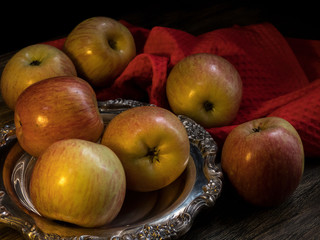 Apples and silver plate on the dark wooden table
