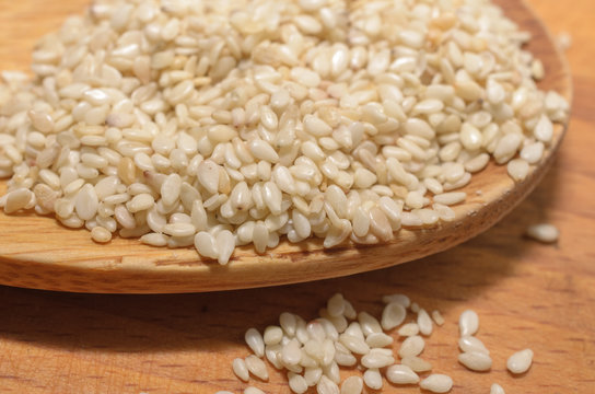 Organic natural sesame seeds on wooden spoon, healthy food background