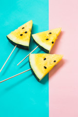 three triangular ice cream slices on a stick of ripe yellow watermelon