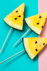 three triangular ice cream slices on a stick of ripe yellow watermelon