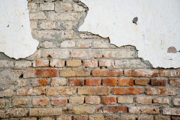 Old brick wall with damaged white plaster