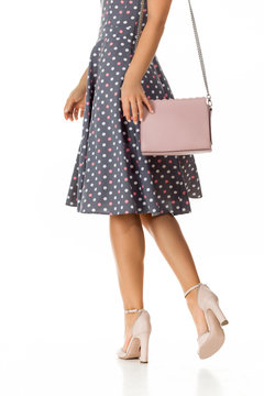 pink women's shoes and leather bag. Beautiful female legs wearing summer high heeled sandals in polka-dot dress and pink woman handbag on white background.