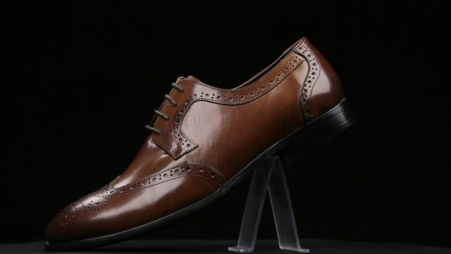 Rotation and approximation of brown classic men's shoes on a black background. Copy space.