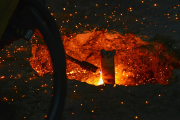 A gas cutter in production, a welder removes unnecessary metal residues with a gas cutter, sparks fly in different directions.