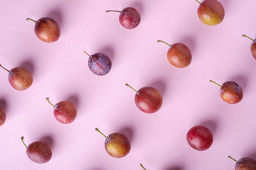 Ripe sweet plum fruits pattern texture, top view, flat lay, pink background