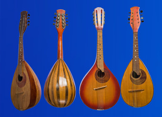 Four different mandolins isolated on blue background. Baroque string musical instruments.