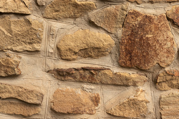 Background in the form of a stone wall made of many flat buta stones of light brown color