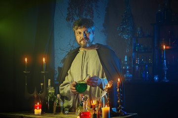 portrait of  wizard with burning candles and magic potions