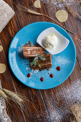 Ice cream and cake on a blue plate on a brown wooden background