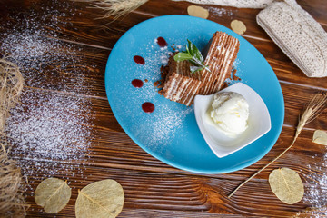 Ice cream and cake on a blue plate on a brown wooden background