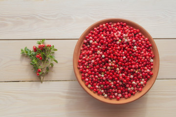 Fresh ripe  lingonberry (cowberry , partridgeberry, foxberry) in clay bowl on rustic wooden table top view