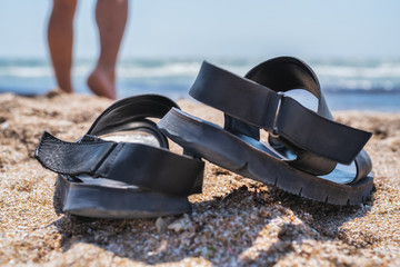 black leather sandals on a sandy beach against the background of the sea
