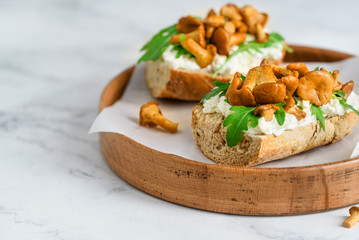 Two sandwiches with chanterelles, arugula and cream cheese. Ciabatta with mushrooms and cheese....