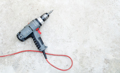 Electric drill lies on a gray grunge concrete background