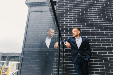 a man in a suit looks into the distance on the balcony