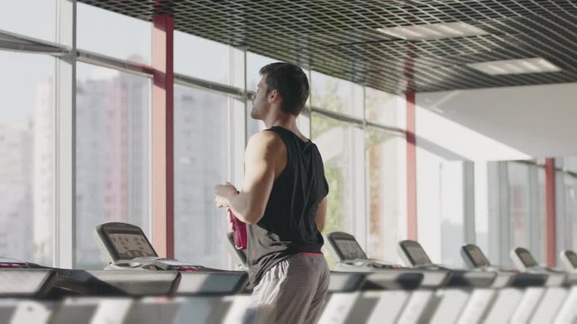 Runner man drinking water from bottle at intensive training on treadmill machine