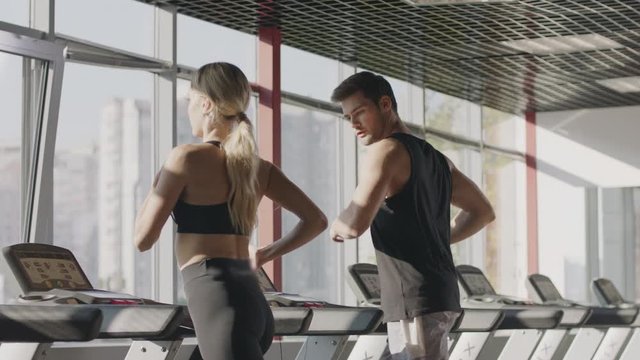 Fitness couple running on treadmill machine in gym club together