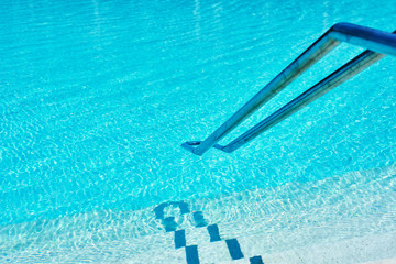 Background of water in blue swimming pool, water surface with a sun reflection
