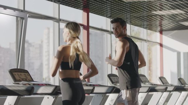 Running couple training cardio exercise on treadmill machine in fitness center - Powered by Adobe