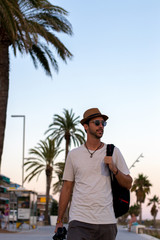 Fototapeta na wymiar Modelo paseando delante de la playa con sombrero y gafas