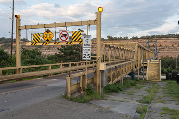 Large yellow steel girder bridge crossing river with mountainside in background