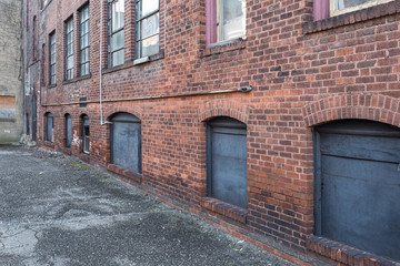 Angled view of red brick wall with windows in alley